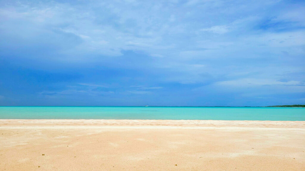 Sailboat anchored in beautiful water off a sandy beach